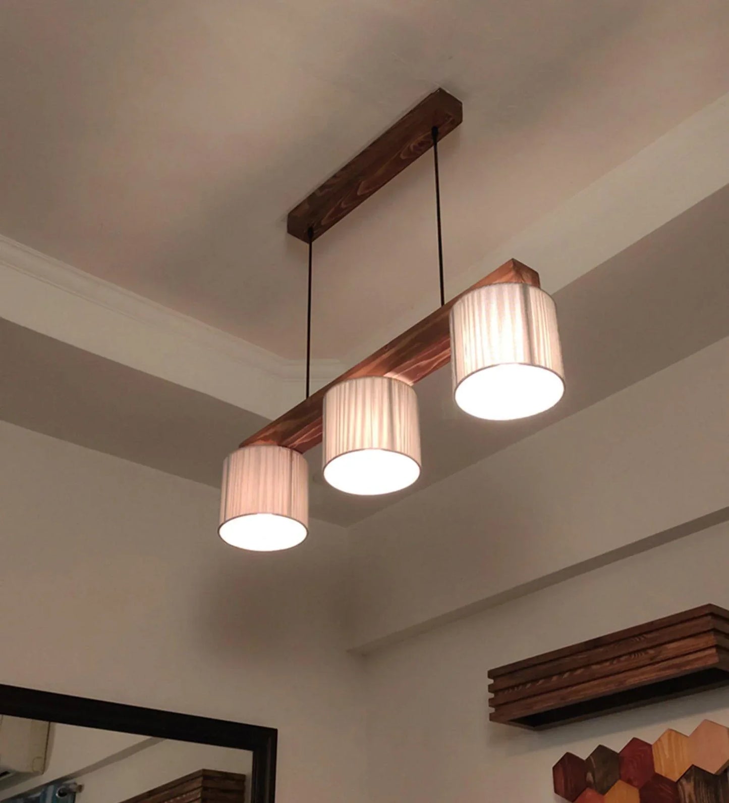 Ceiling light fixture with wooden beam and fabric shades on a ceiling.