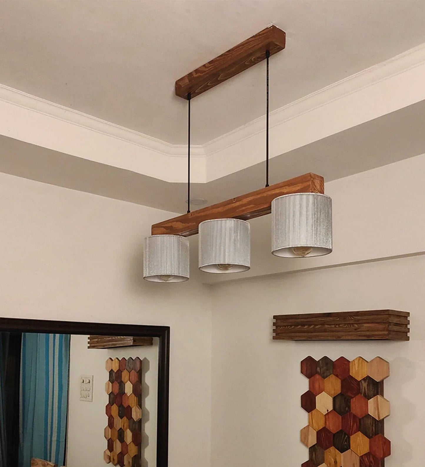 Modern ceiling light fixture with wooden beams and white lampshades in a room setting.