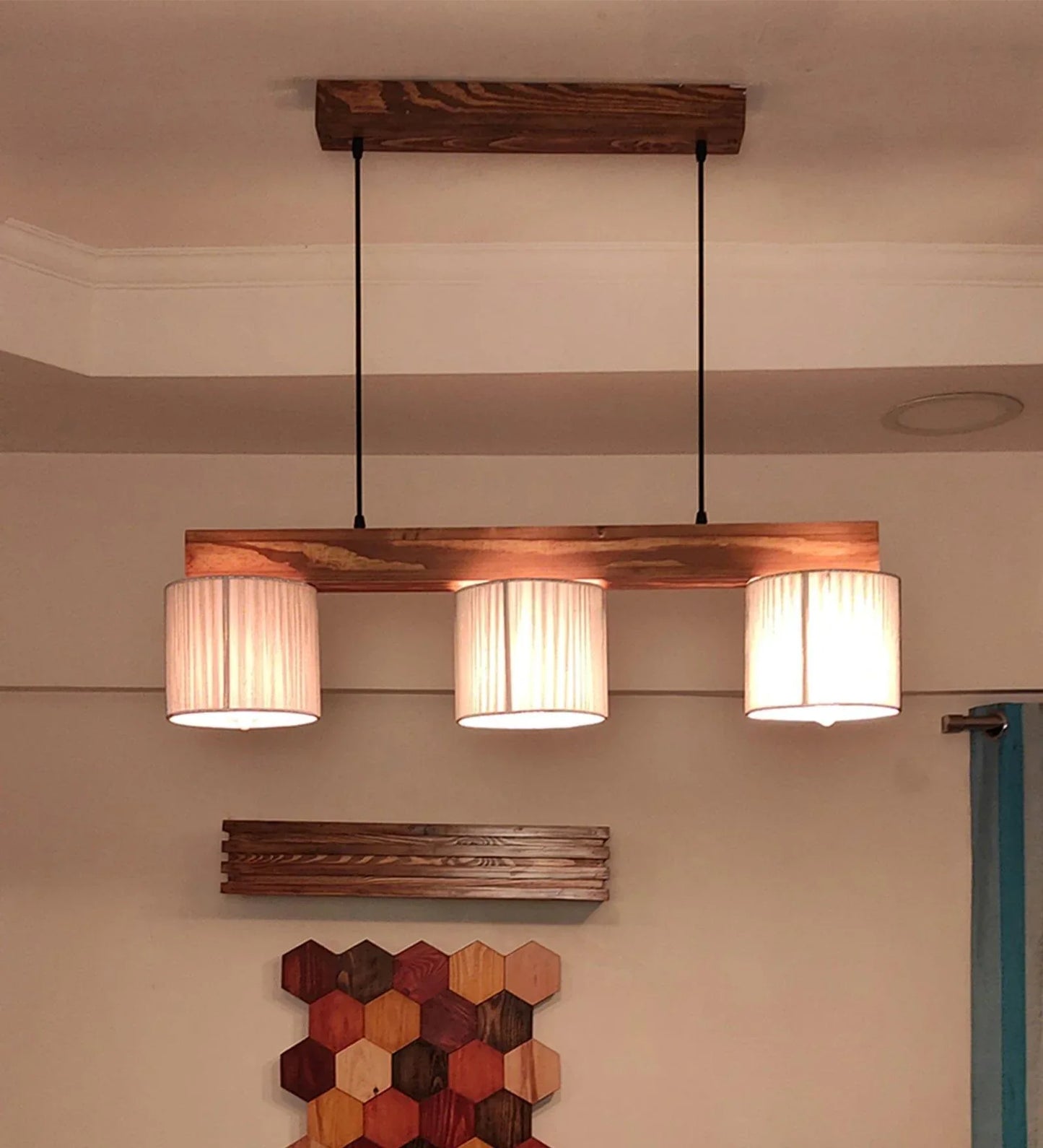 Wooden pendant light fixture with three lampshades hanging from the ceiling.