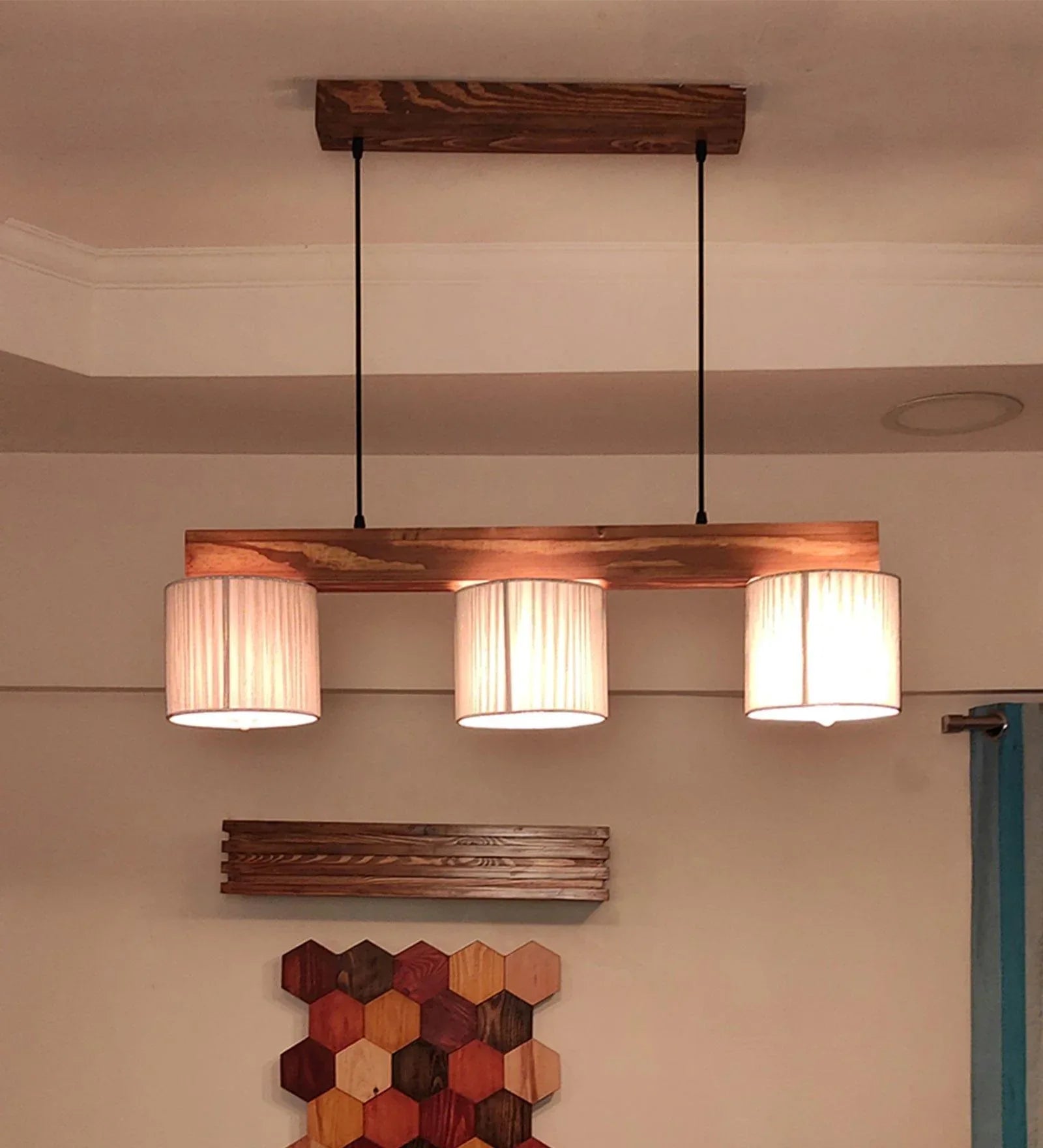 Wooden pendant light fixture with three lampshades hanging from the ceiling.