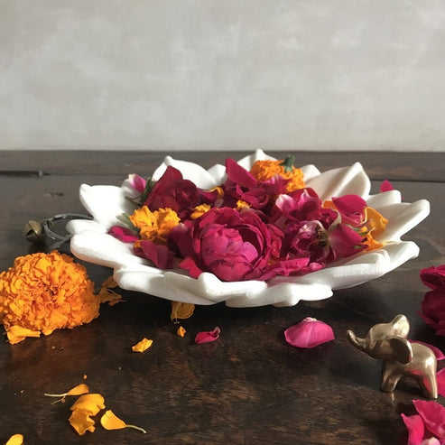 Decorative white dish with red and pink flowers on a wooden surface.