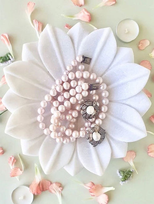 Pearl jewelry set on a large white flower with small pink flowers around