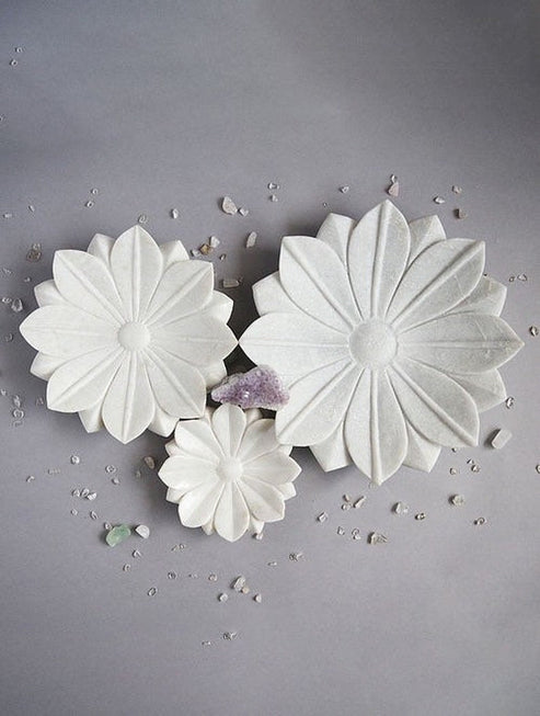 Three white flower-shaped meringues on a gray background with small decorative elements.