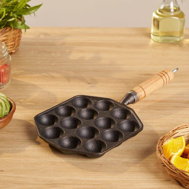Cast iron pan with multiple small compartments on a wooden surface