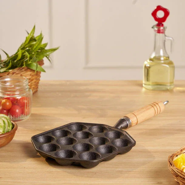 Cast iron pan with wooden handle on a kitchen counter with vegetables and oil bottle