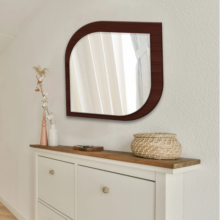 Wooden mirror with wicker basket and vase on a white cabinet against a beige wall