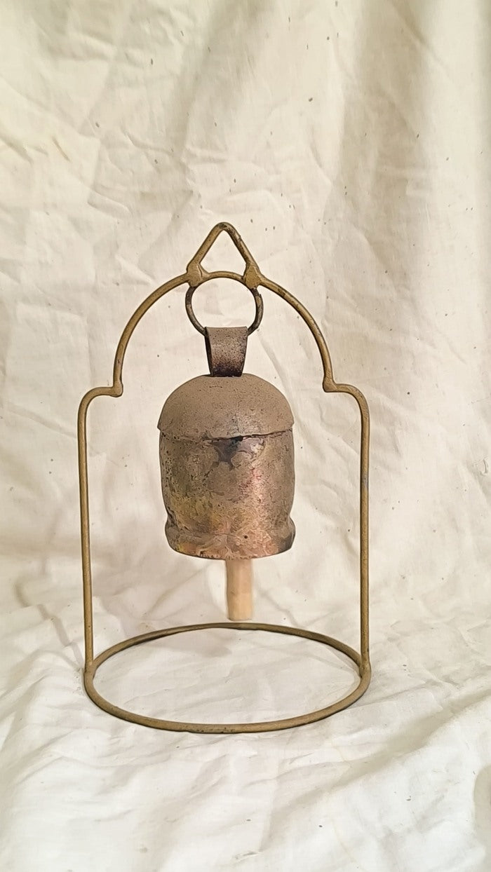 Decorative brass bell with metal stand on a textured beige background