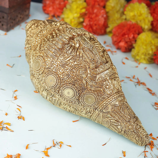 Decorative gold object with intricate patterns on a light blue background with flowers.