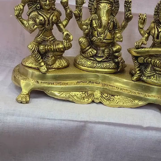 Handcrafted 9-inch solid brass Lakshmi Ganesha Saraswati trio idol set on ornate footed base — three deities together in warm antique gold finish — ArtyCraftz