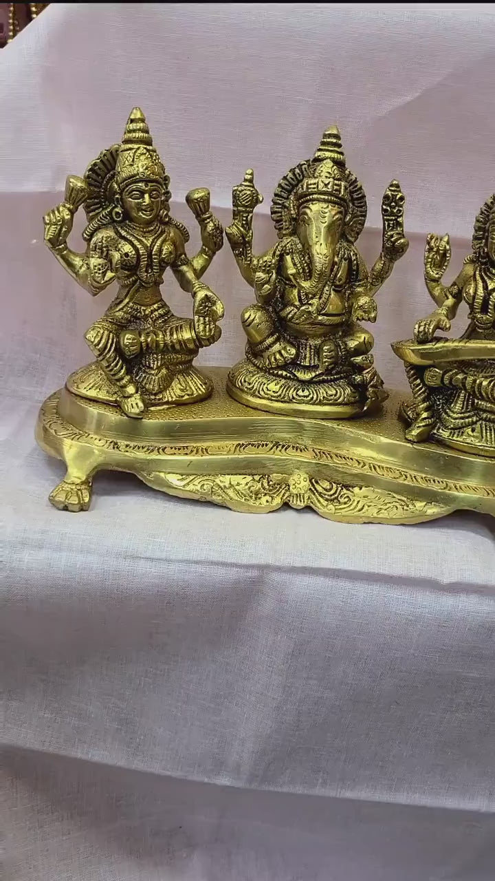 Handcrafted 9-inch solid brass Lakshmi Ganesha Saraswati trio idol set on ornate footed base — three deities together in warm antique gold finish — ArtyCraftz